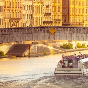 a sightseeing boat under a bridge during sunset