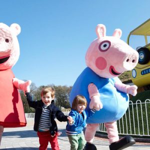 two kids walking with mascot in peppa pig world