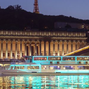 a large sightseeing ship at night with light reflecting in the waters