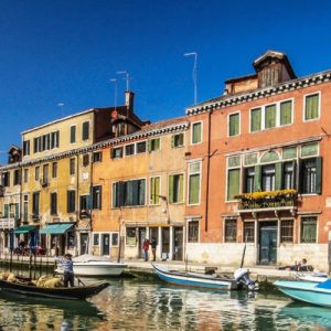gondola in the middle of a Venetian canal with parked gondolas on the side