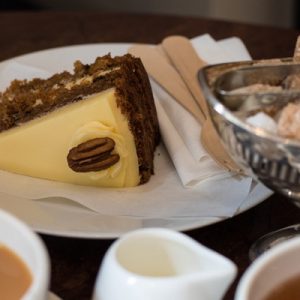 English dessert on a white plate with some snacks on the right; there are two cups of coffee below