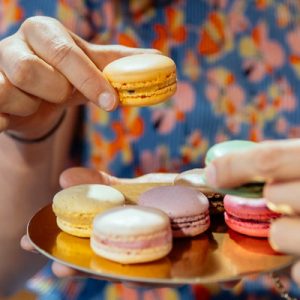 a platter of colorful macaroons and people are picking them up