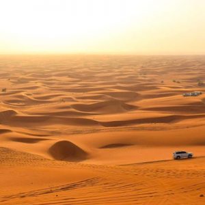 sand dunes with cars for dune bashing during the evening desert safari