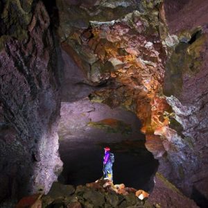 person standing inside Vidgelmir Lava Cave